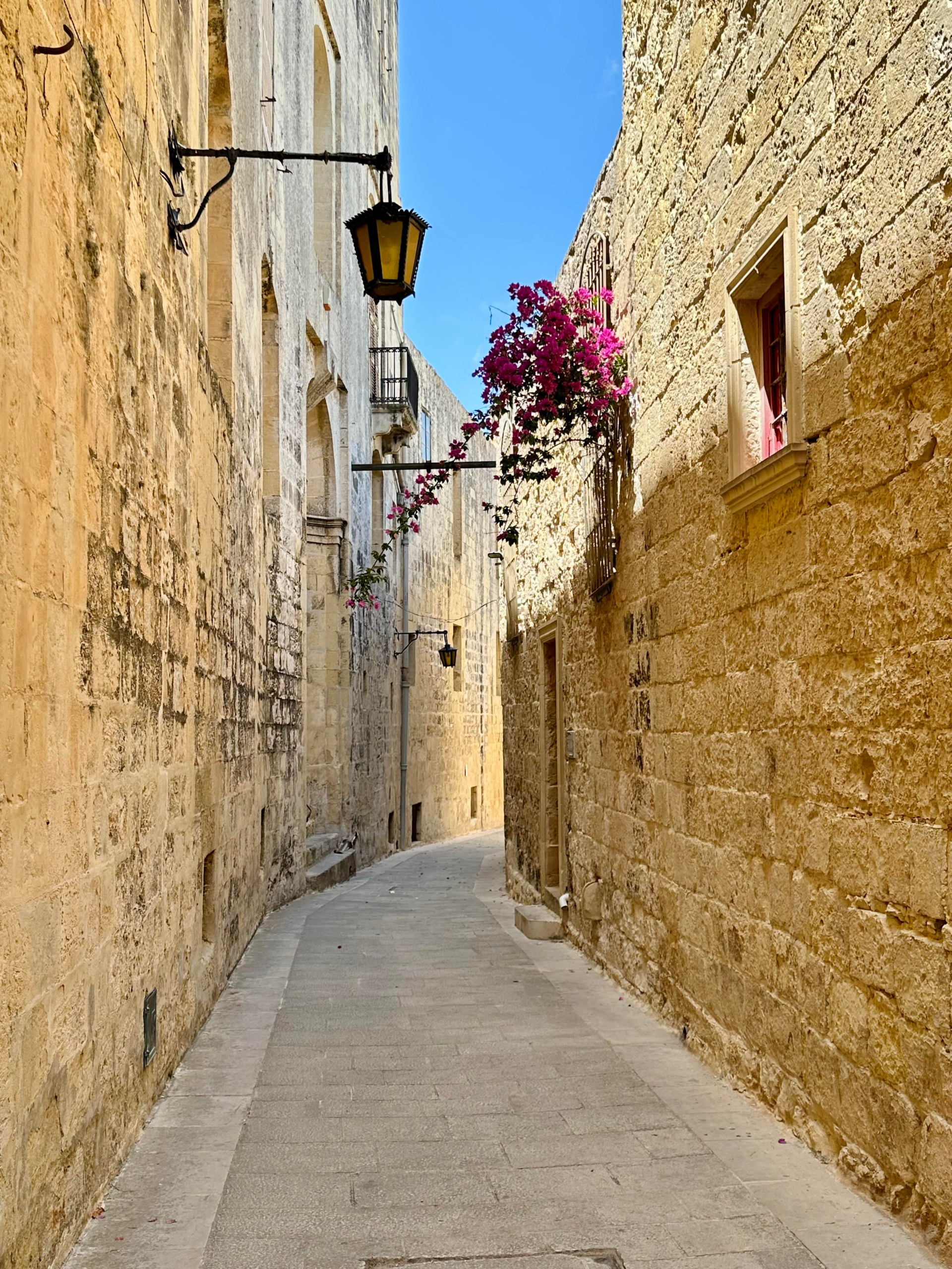 Sunlit alley in Mdina, Malta, showcasing the medieval streets and stone architecture.