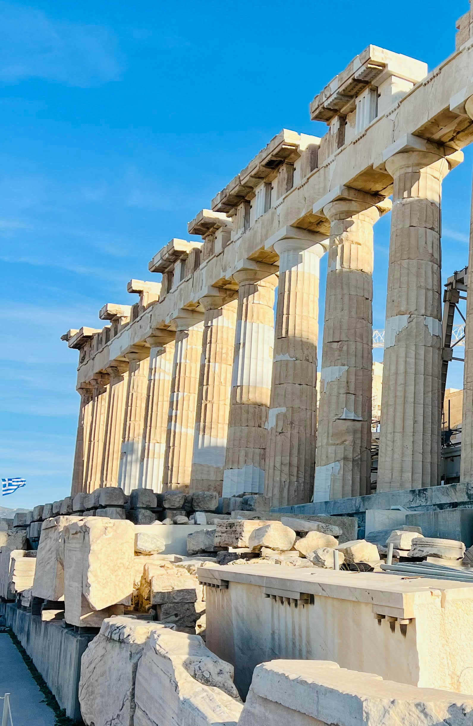 The Parthenon temple on the Acropolis in Athens, Greece, bathed in sunlight against a clear sky.
